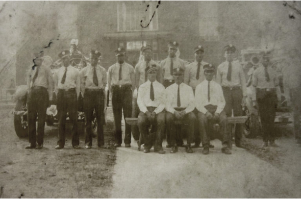 Photo of 12 uniformed members of the Halls Hill Volunteer Fire Department in front of their fire apparatus.